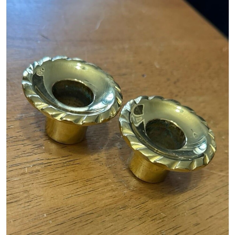 Two brass candlestick holders with scalloped edges